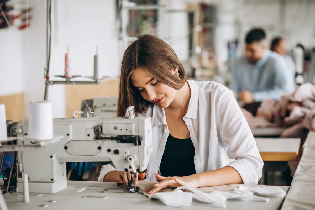Tekstil atölyesinde dikiş makinesi başında çalışan üretim personeli